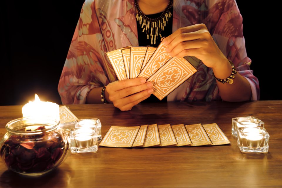 Tarotista con cartas en la mano y otras apoyadas sobre la mesa